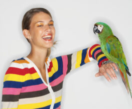portrait of a woman sitting with a parrot on her arm